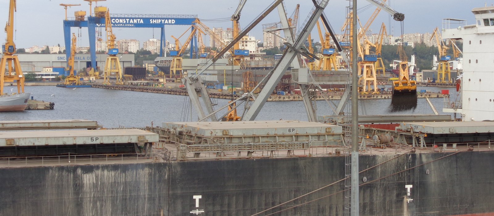 Cargou la cheu în portul Constanța, cu macarale galbene și un șantier naval în fundal