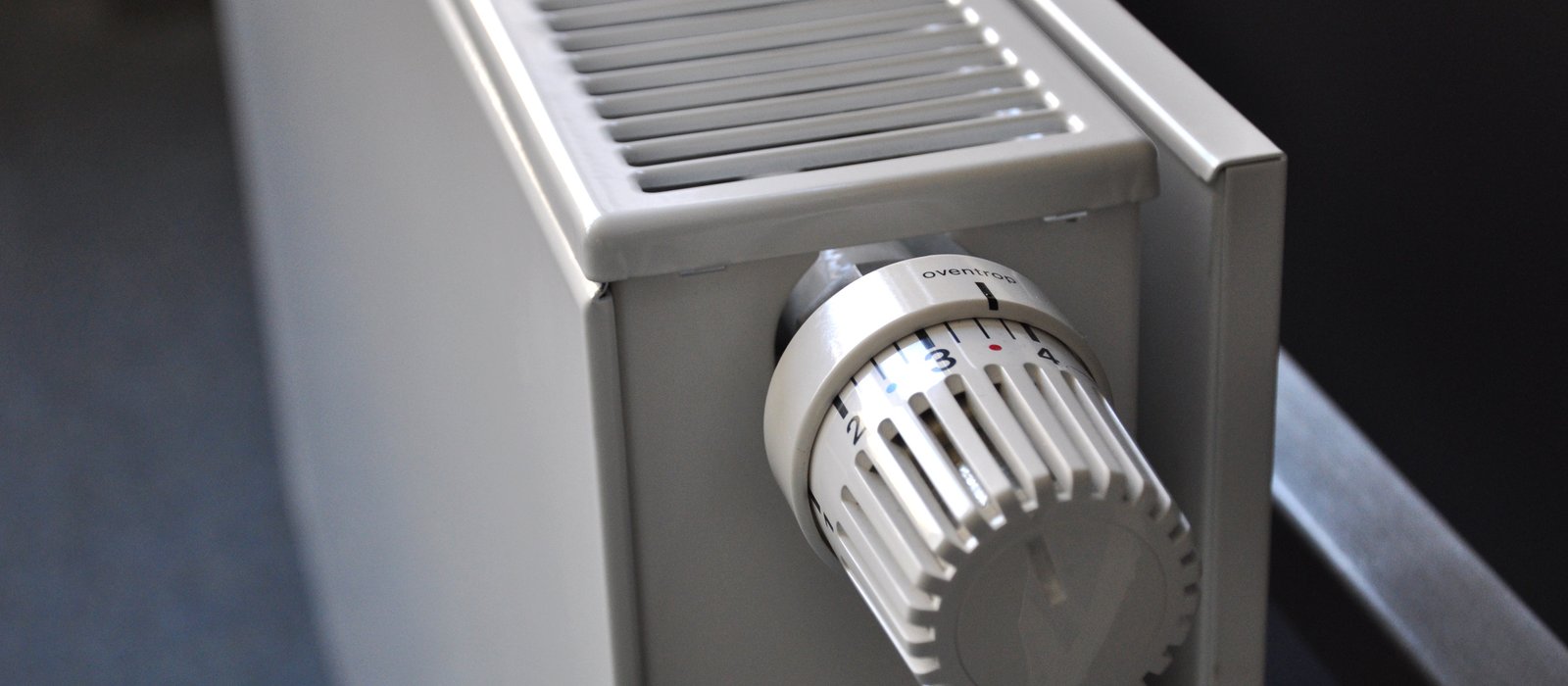 Radiator alb de încălzire central montat pe un perete, cu țevi la bază