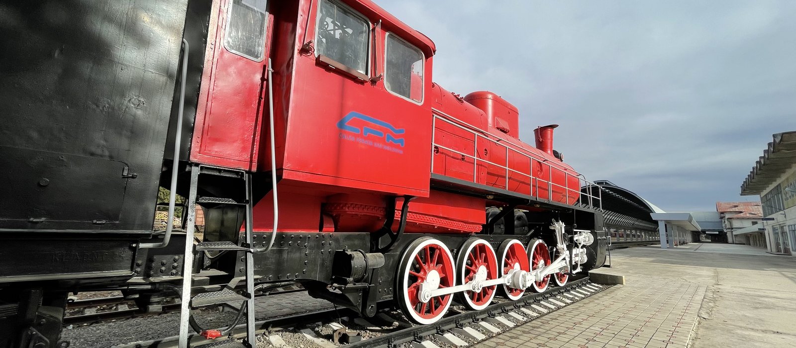Locomotivă cu abur roșie cu sigla CFM, expusă pe peronul gării centrale din Chișinău