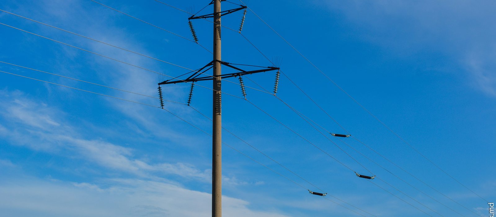 Stâlpi metalici de înaltă tensiune cu linii electrice aeriene pe un câmp, lângă municipiul Bălți, în Republica Moldova