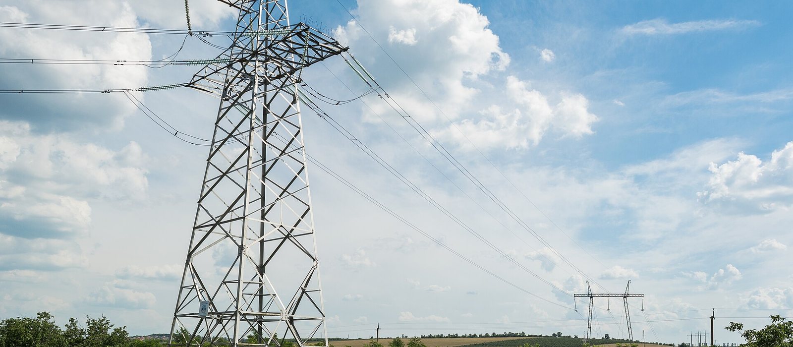 Stâlp de înaltă tensiune și linii electrice lângă drumul M5 în apropiere de Bălți, cu dealuri cultivate în fundal