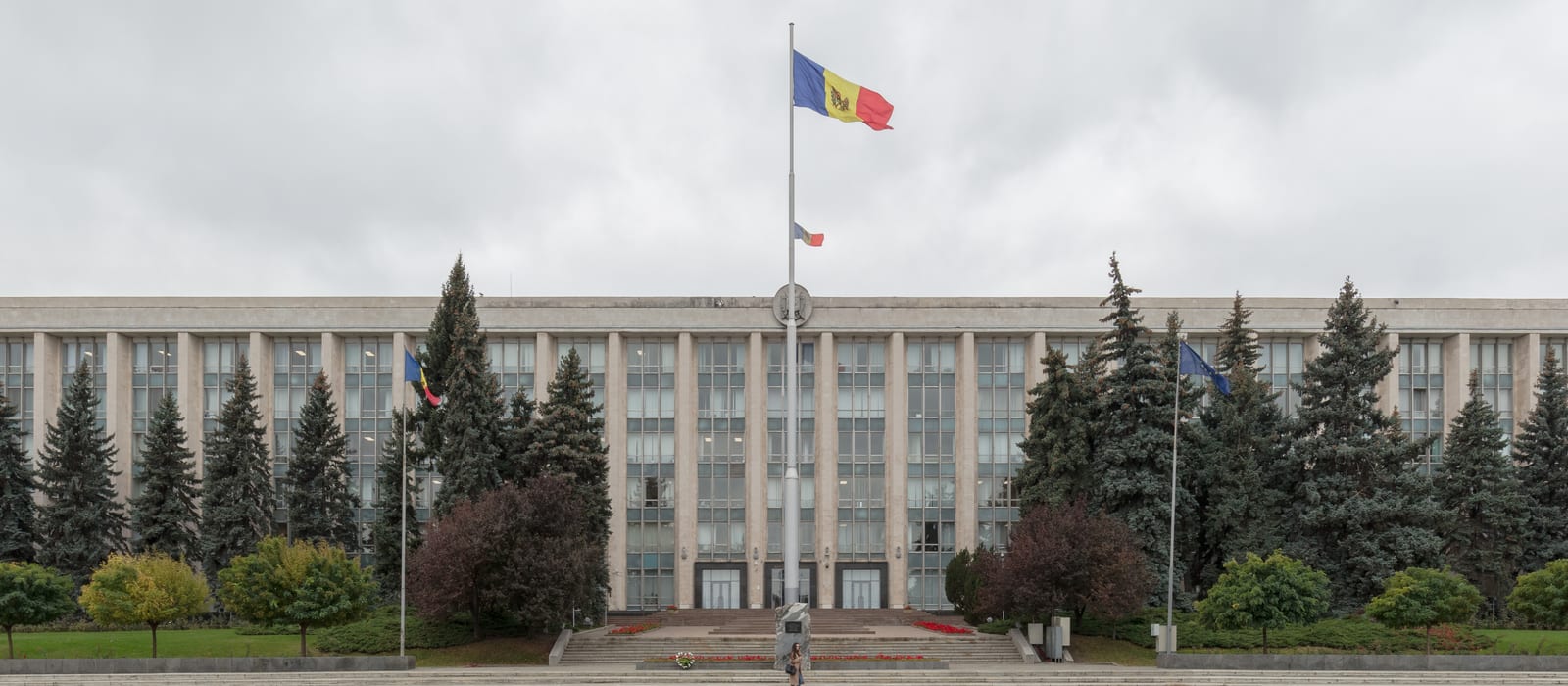 Fațada Casei Guvernului din Chișinău, cu drapelul Republicii Moldova pe catargul central și drapelul Uniunii Europene în dreapta, între brazi