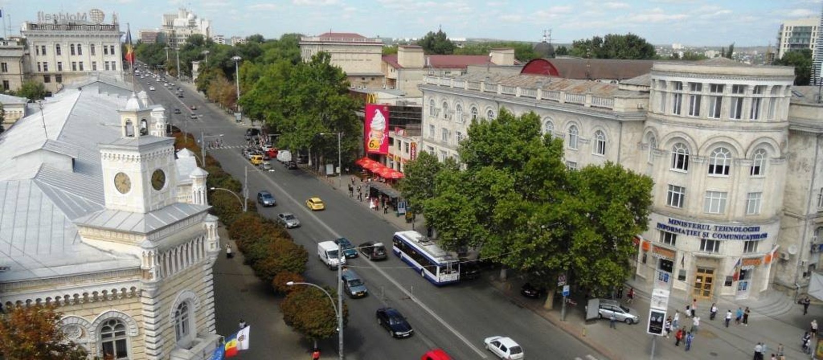 Bulevardul Ștefan cel Mare din Chișinău văzut de sus, cu primăria în stânga, un troleibuz pe carosabil și clădiri din piatră pe dreapta