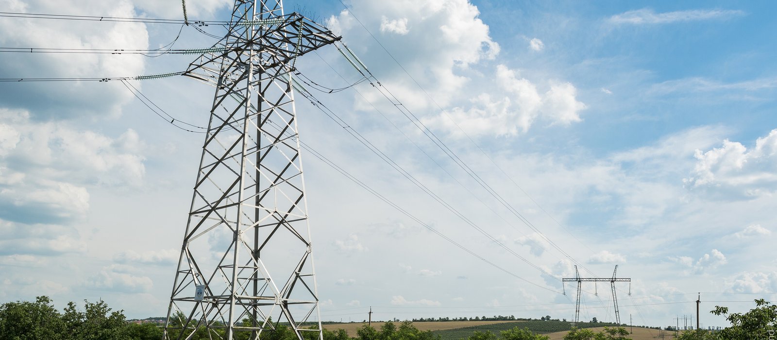 Stâlpi de înaltă tensiune pe un câmp lângă Bălți, cu linii electrice care se pierd spre orizont
