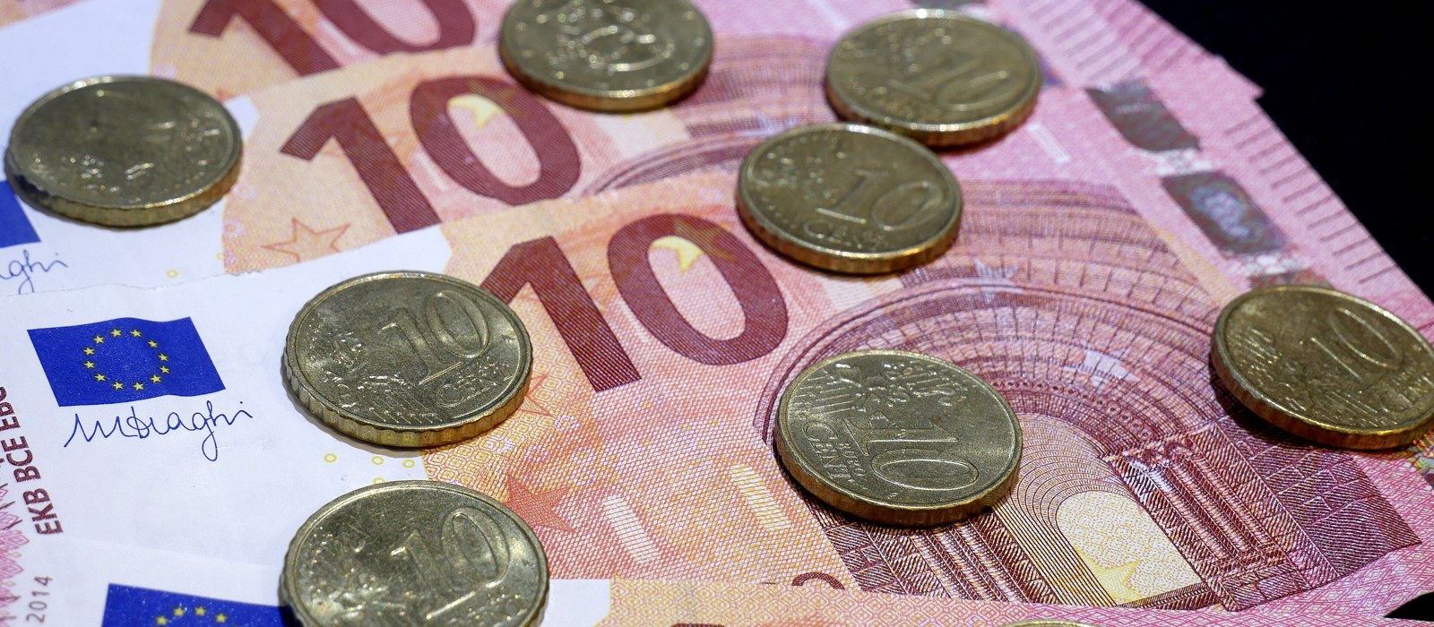 Două bancnote de zece euro și monede de zece eurocenți așezate pe o suprafață