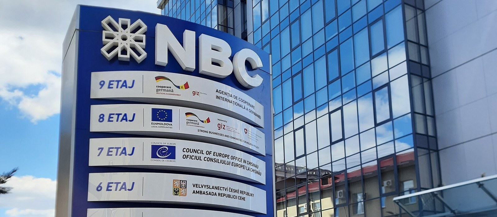 Panoul cu firmele din clădirea de birouri NBC, cu fațadă de sticlă, în Chișinău