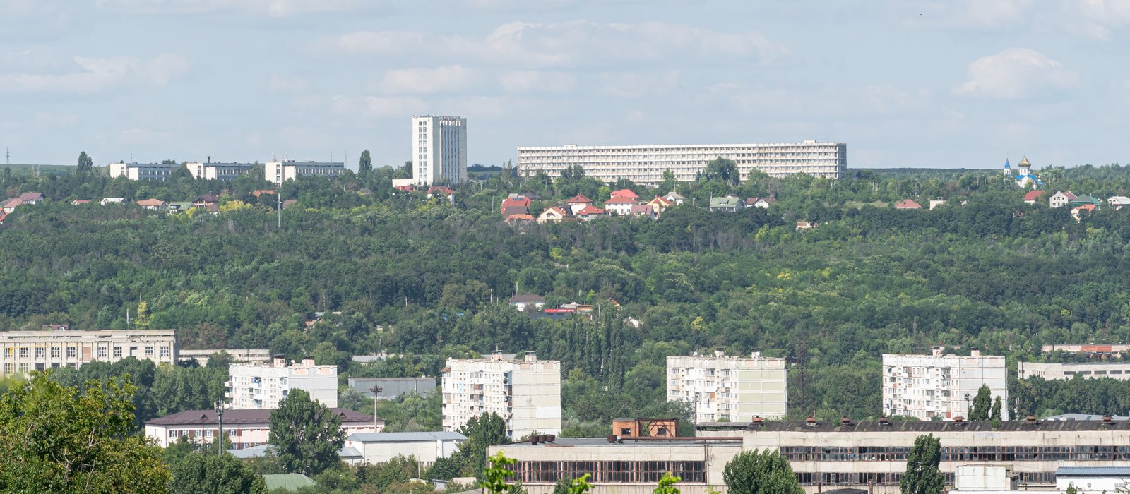 Cartier industrial din Chișinău, cu hale și clădiri de producție printre blocuri și copaci