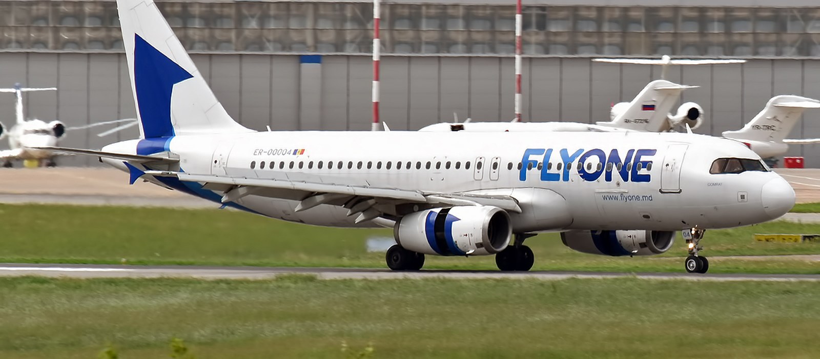 Un Airbus A320 alb cu însemnele FlyOne și înmatricularea ER-00004 rulează pe pistă