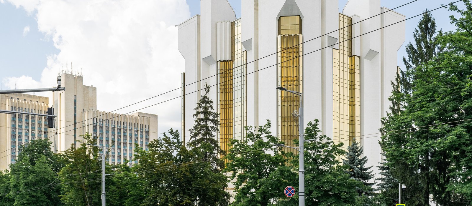 Palatul Prezidențial din Chișinău, clădire albă cu geamuri aurii, văzut printre copaci