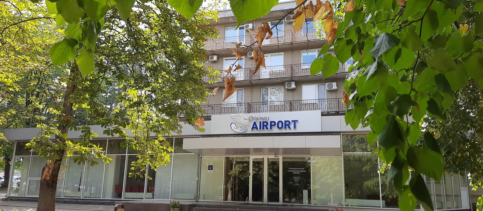 Clădirea terminalului Aeroportului Internațional Chișinău, cu intrarea și parcarea din fața ei