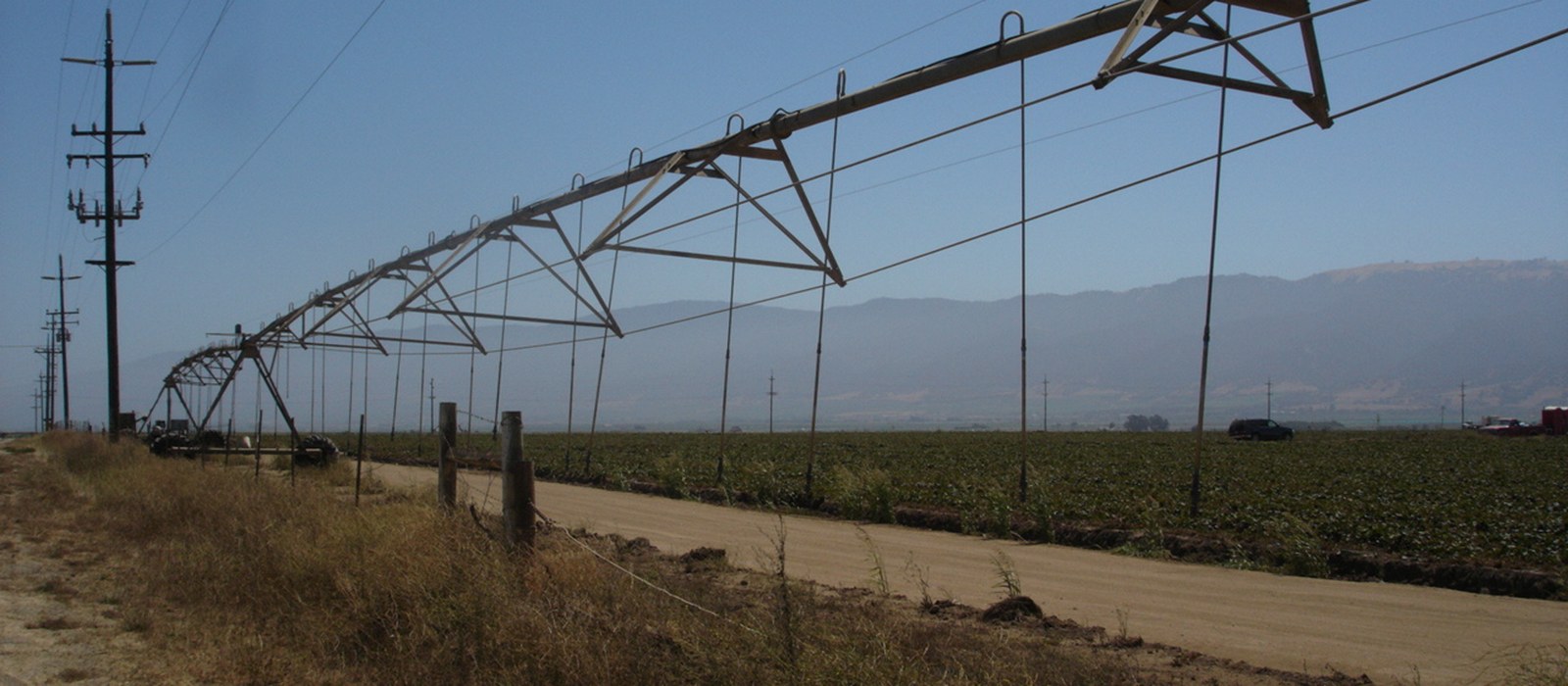 Sistem de irigare cu aspersoare pe un câmp agricol, cu conducte și jeturi de apă