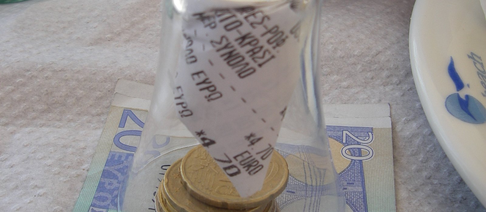 O bancnotă de 20 de euro așezată peste o grămadă de monede euro de valori diferite