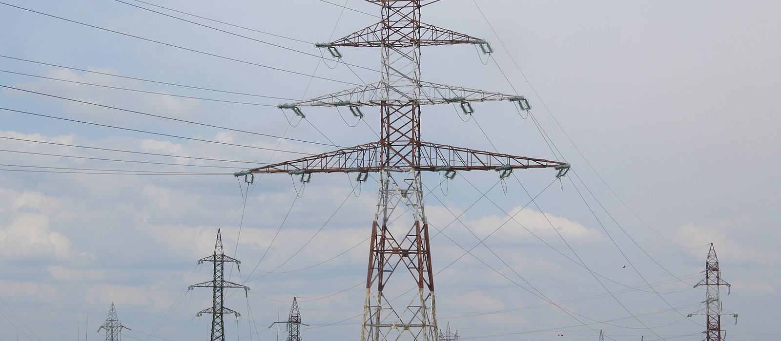 Stâlp înalt al unei linii electrice de 750 kV pe un câmp din România, sub cer senin