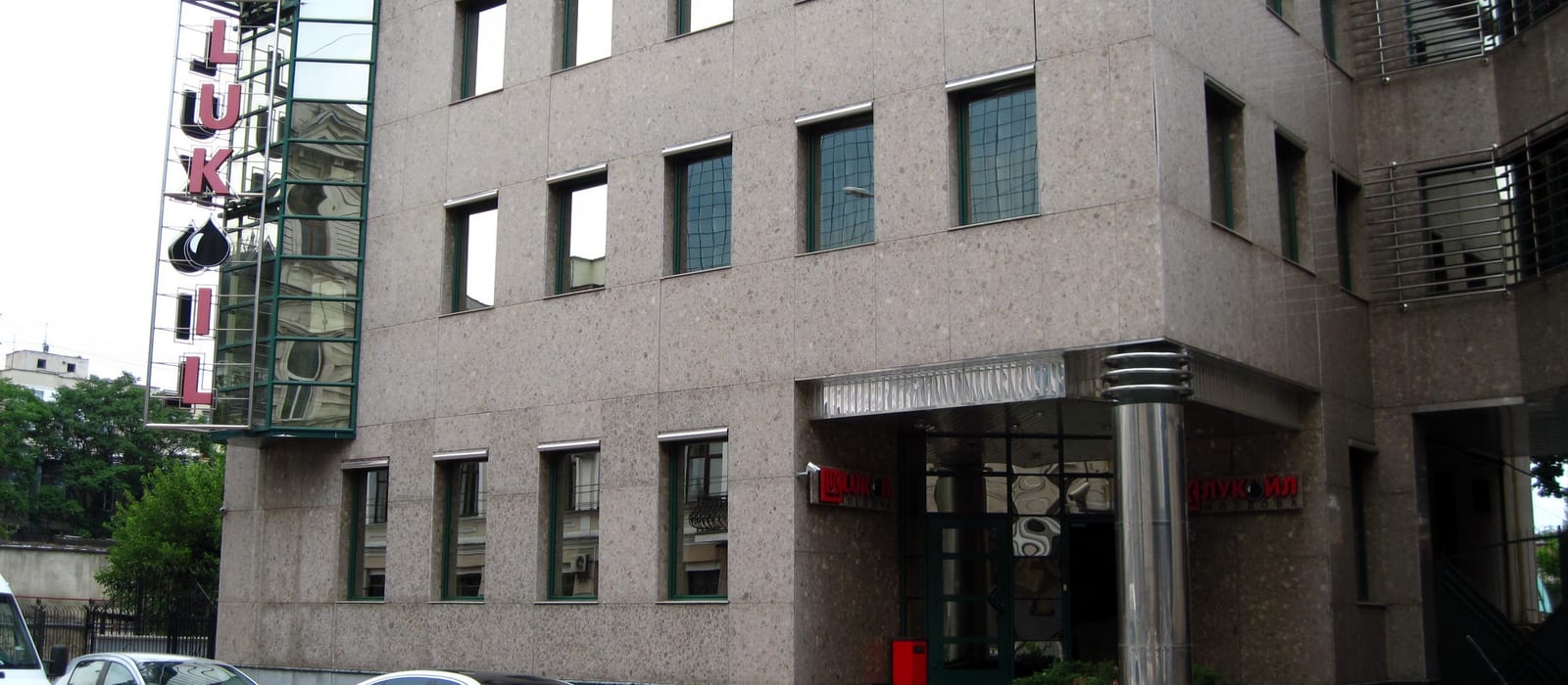 Fațada sediului central Lukoil Moldova din Chișinău, cu firma roșie verticală pe colț și intrarea cu coloană metalică