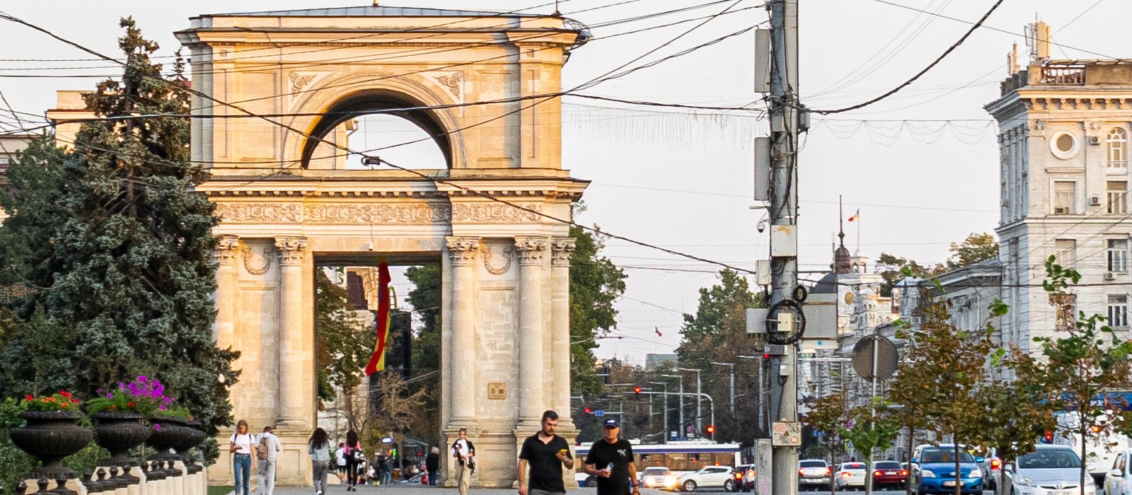 Arcul de Triumf din centrul Chișinăului la apus, cu pietoni pe bulevard