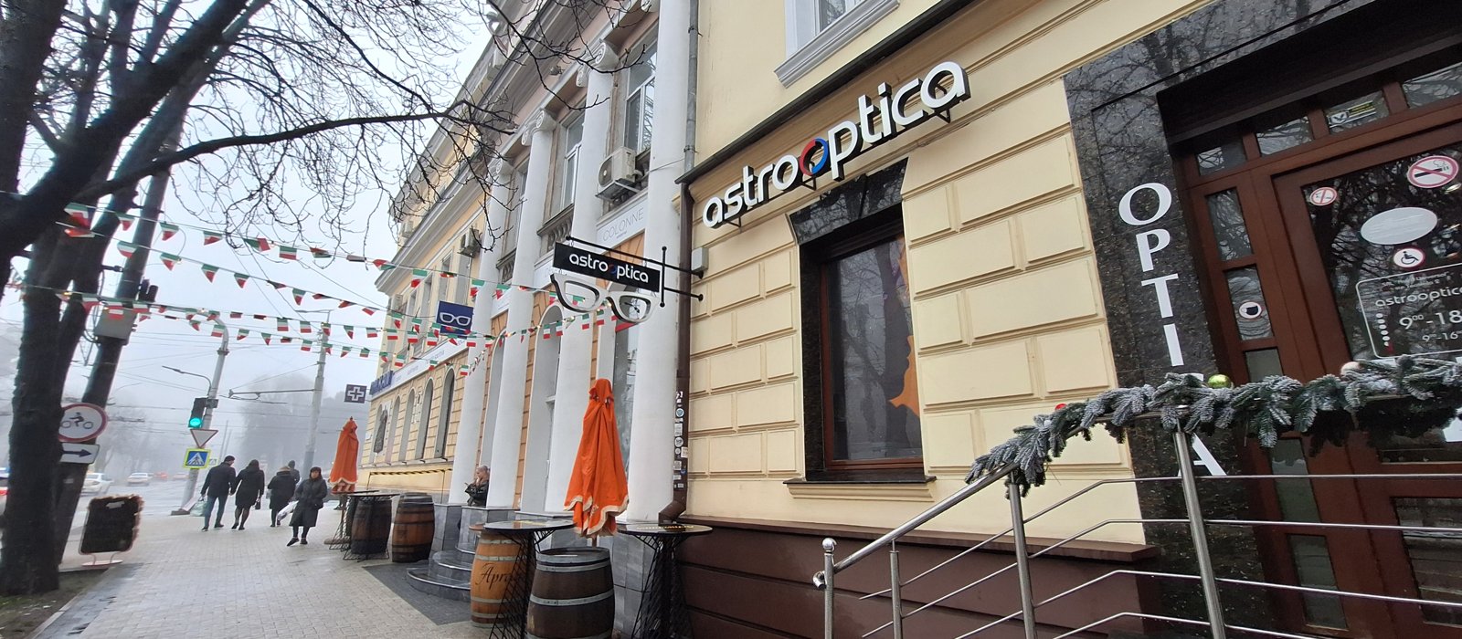 Fațadă comercială cu magazin de optică și ghirlande pe o stradă din centrul Chișinăului, în ceață