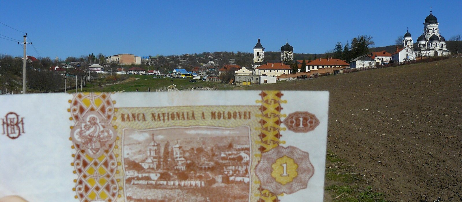 O bancnotă de un leu moldovenesc ținută în fața Mănăstirii Căpriana, clădirea desenată pe reversul ei