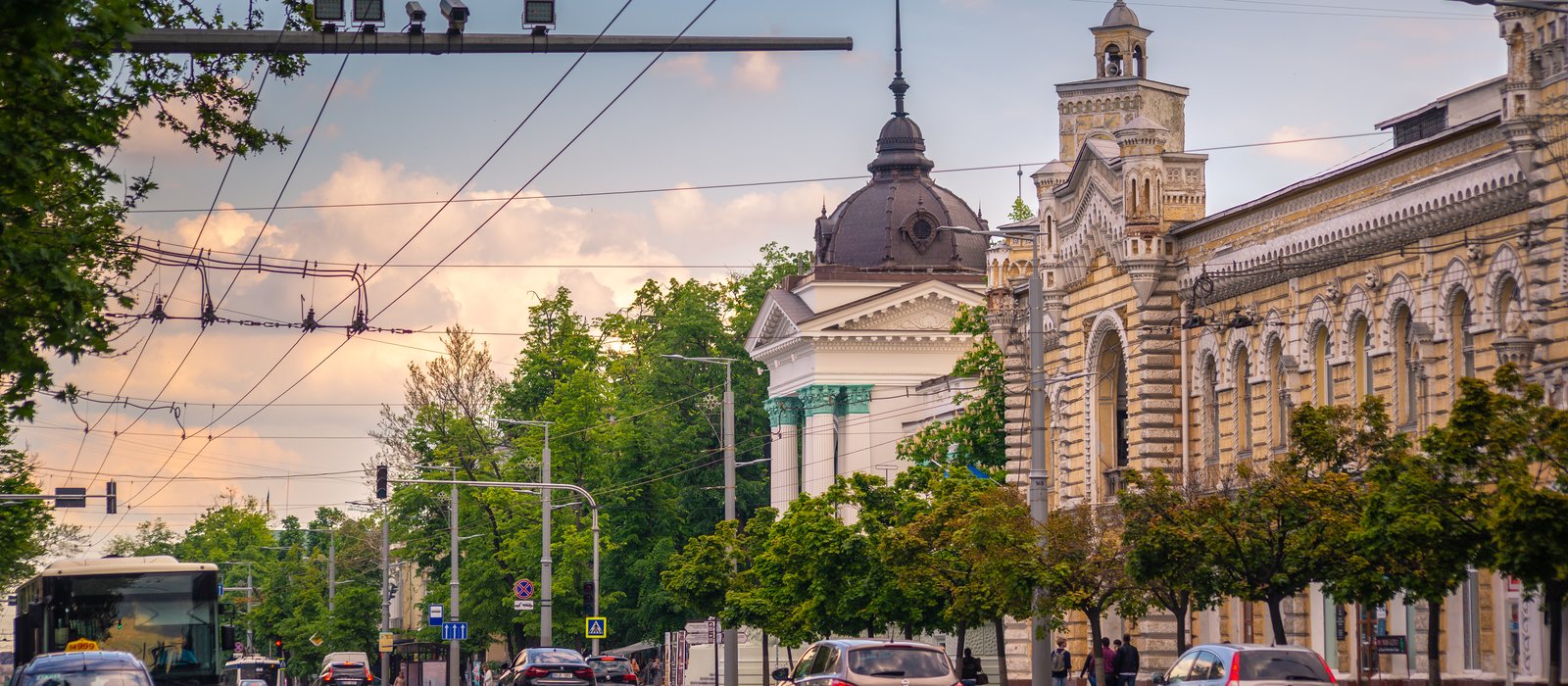 Clădirea primăriei din Chișinău pe o stradă cu troleibuze și mașini, la apus