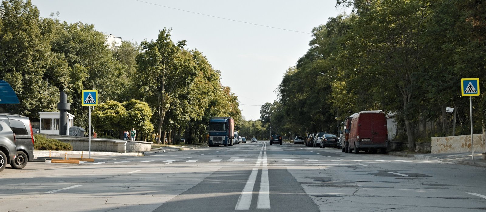 Strada Mihai Sadoveanu din Chișinău, cu copaci pe ambele părți, mașini parcate și o trecere de pietoni