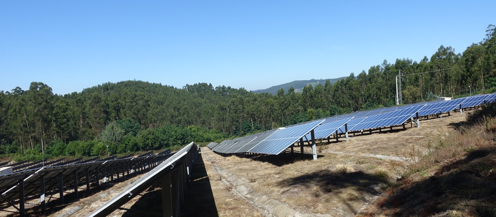 Rânduri de panouri fotovoltaice pe un teren deschis, într-o centrală solară