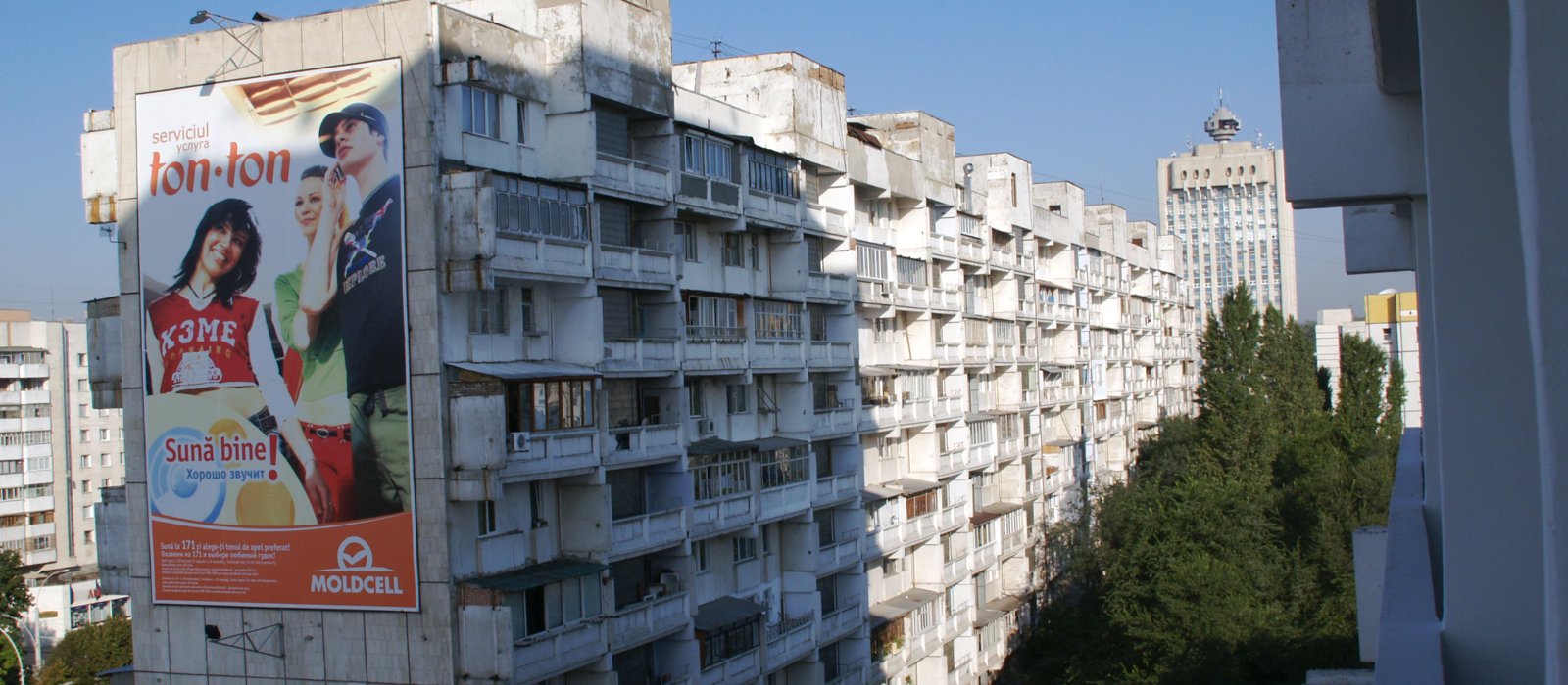 Bloc de locuințe cu zeci de apartamente și balcoane, într-un cartier din Chișinău, cu un turn de birouri în fundal