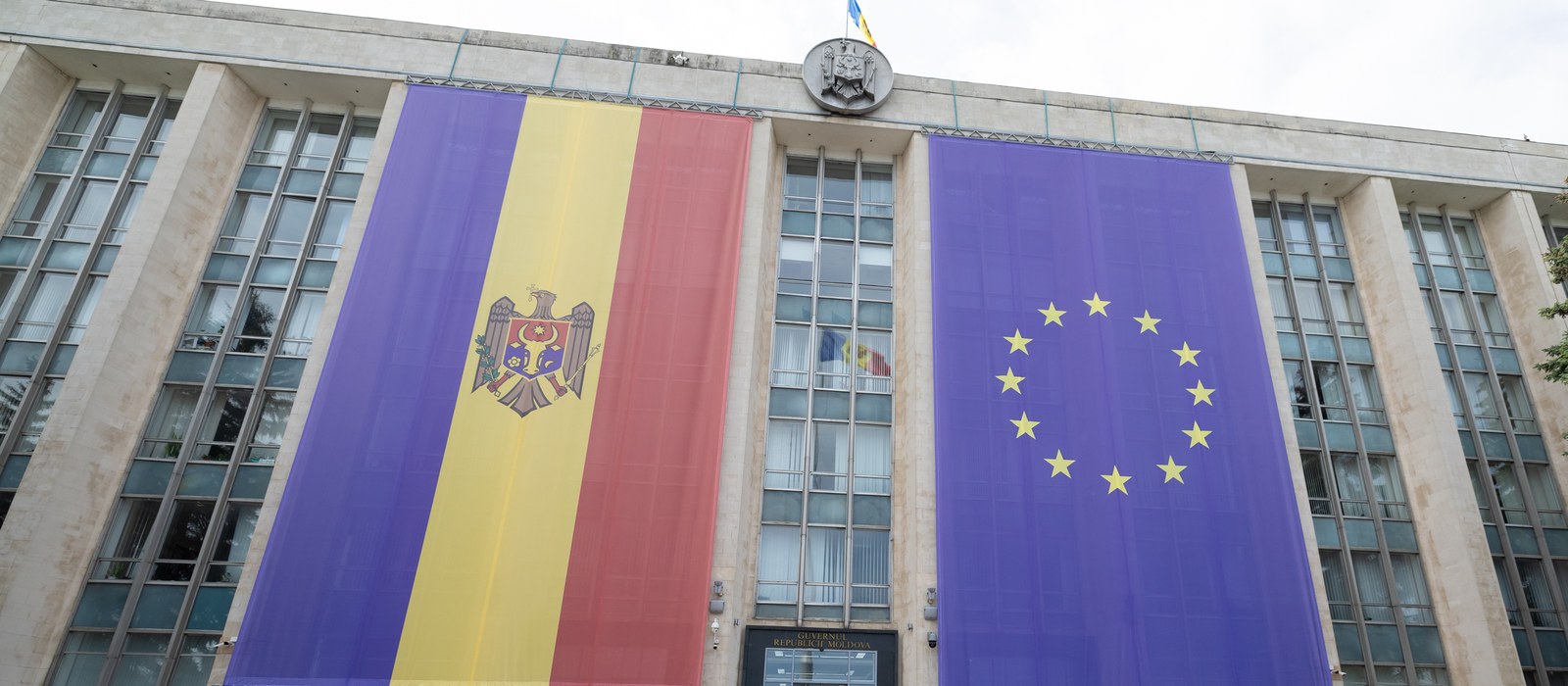 Fațada Casei Guvernului din Chișinău, cu două drapele uriașe, al Republicii Moldova și al Uniunii Europene