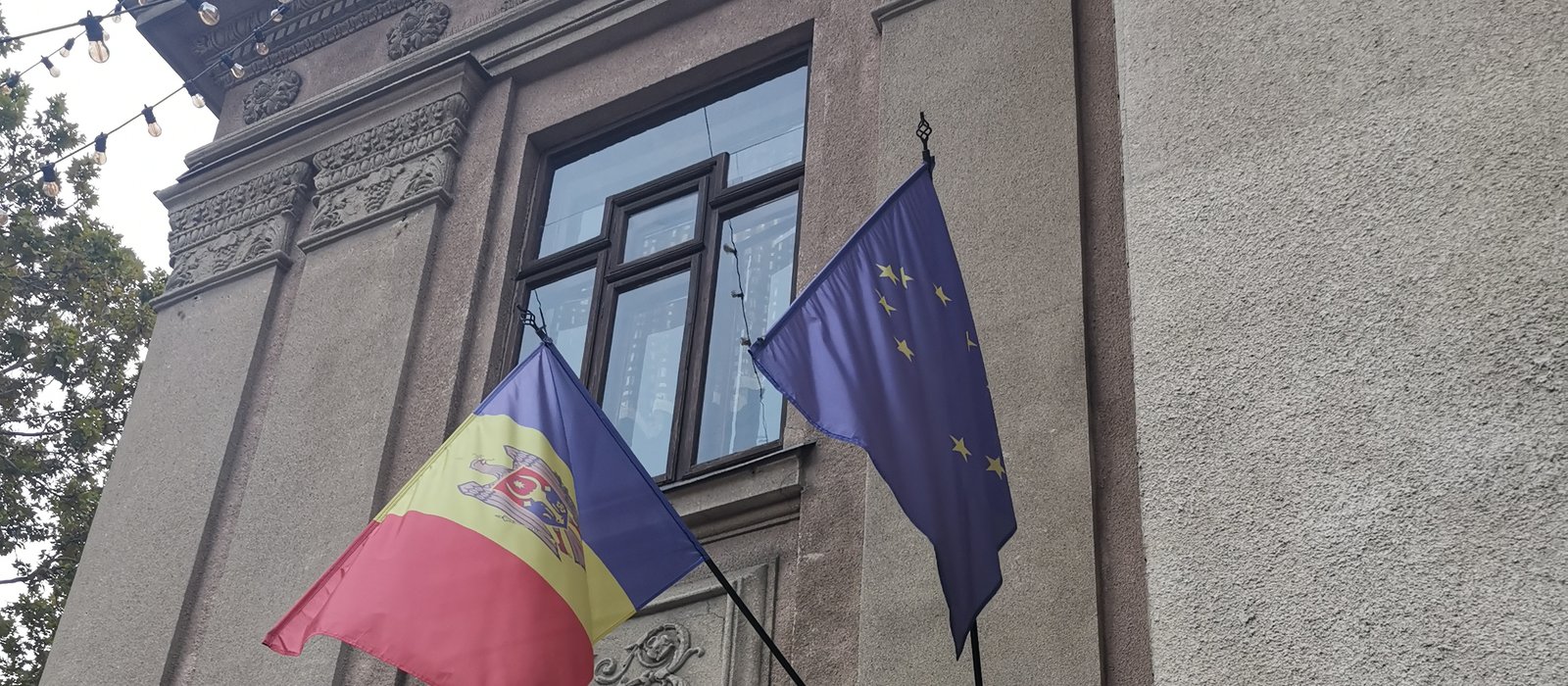 Drapelul Republicii Moldova și drapelul Uniunii Europene, fixate pe fațada unei clădiri vechi din Chișinău