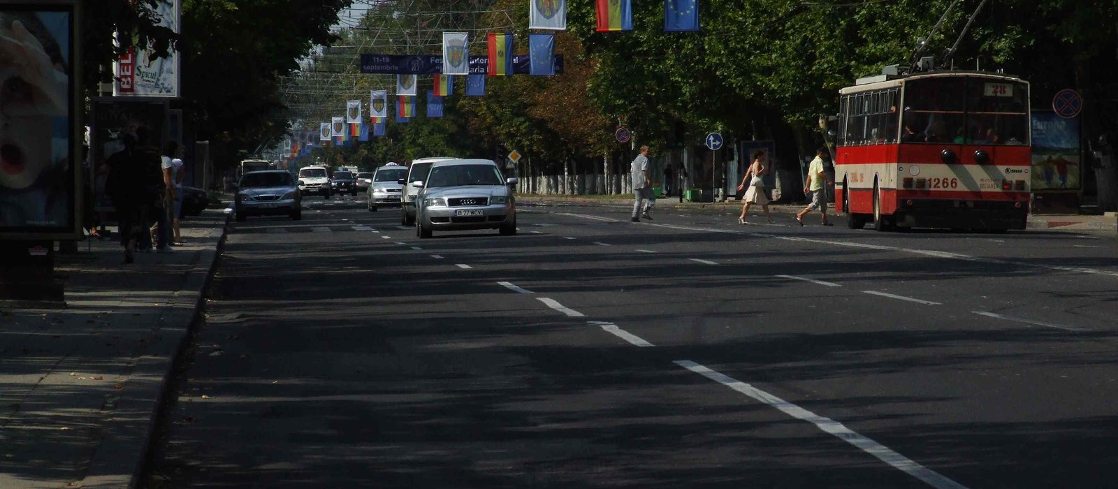 Strada Ștefan cel Mare din Chișinău într-o zi de sărbătoare, cu oameni pe trotuar și clădiri de jur împrejur