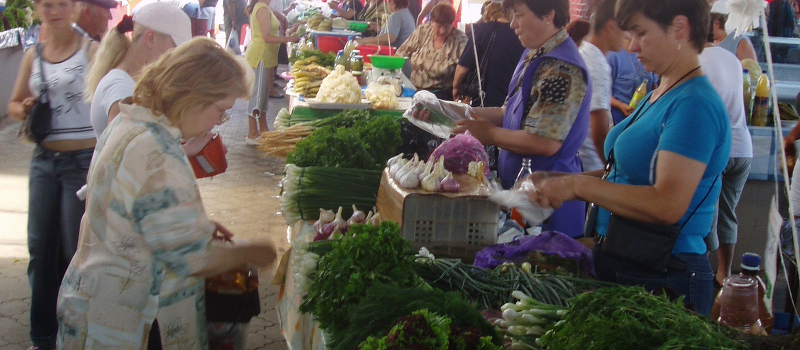 Vânzătoare și cumpărătoare la o tarabă cu verdețuri într-o hală acoperită a Pieței Centrale din Chișinău