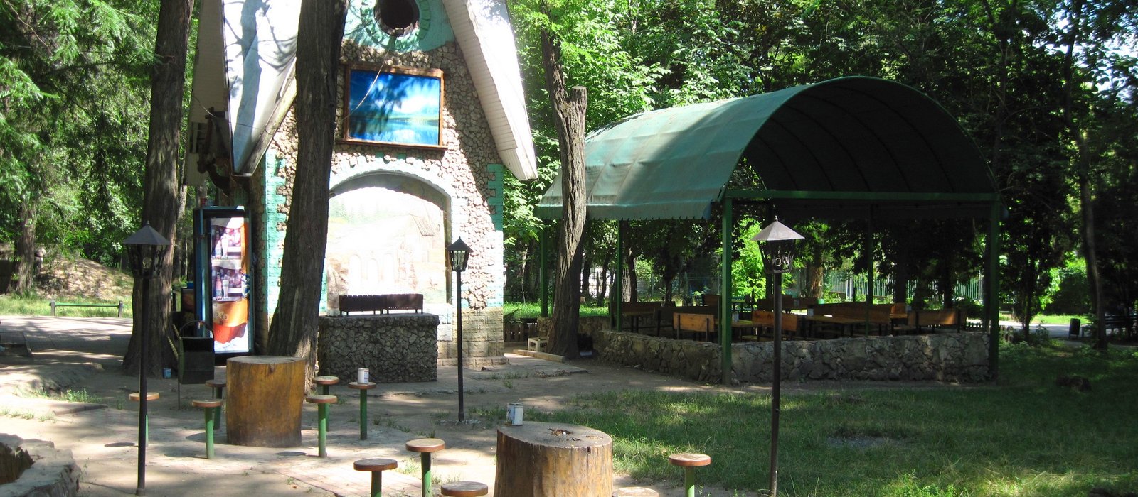 Terasă acoperită cu mese de lemn și un chioșc de piatră într-un parc din Chișinău