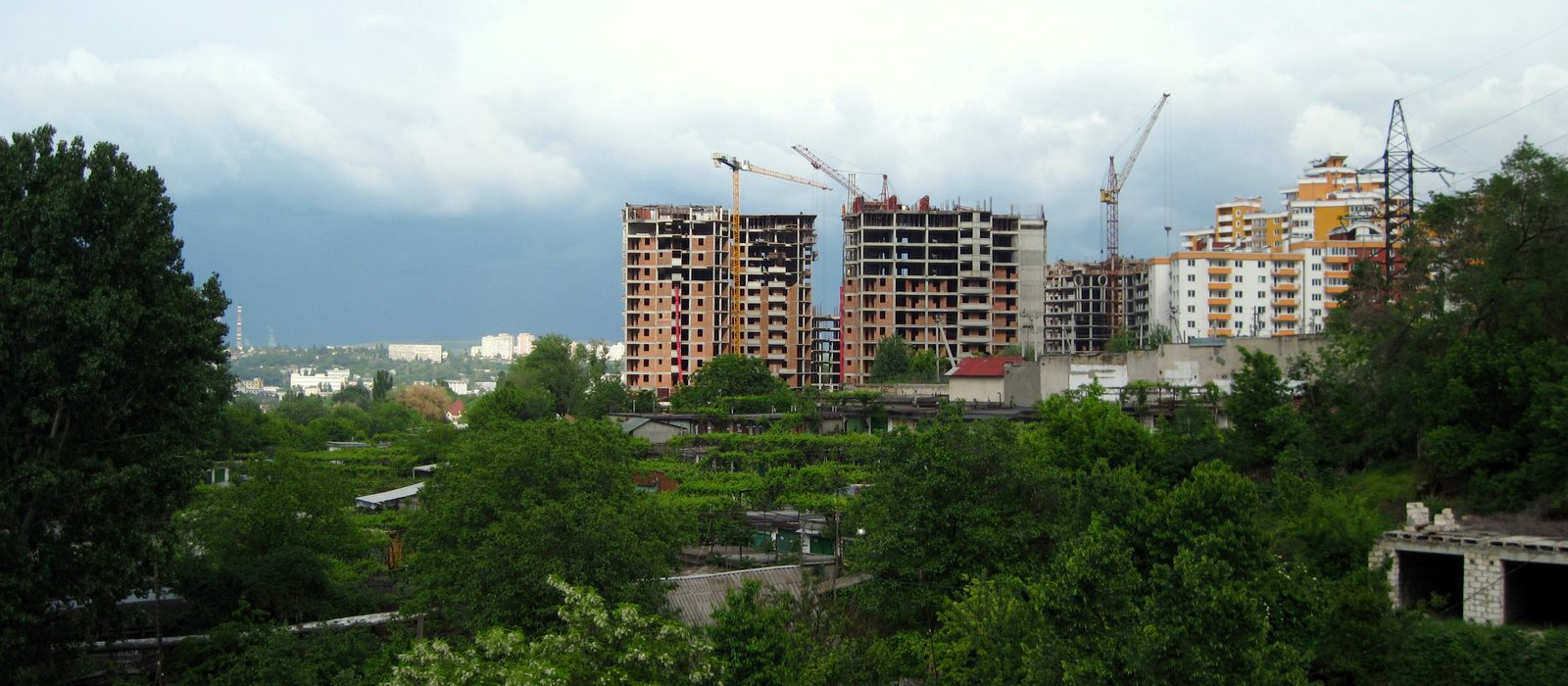 Blocuri în construcție cu macarale, printre grădini și case, în cartierul Valea Trandafirilor din Chișinău