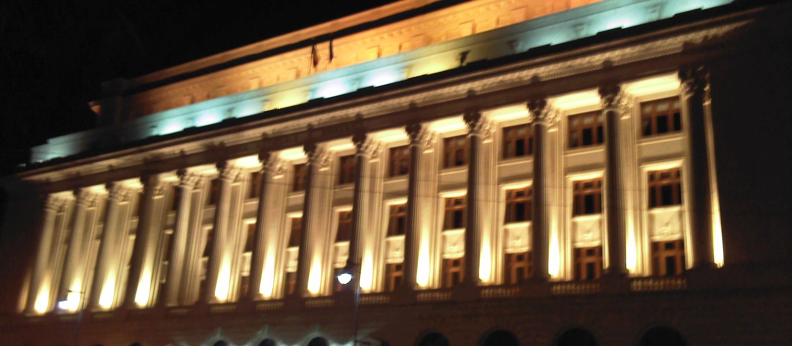Fațada luminată pe timp de noapte a clădirii Băncii Naționale a României din București, cu coloane înalte