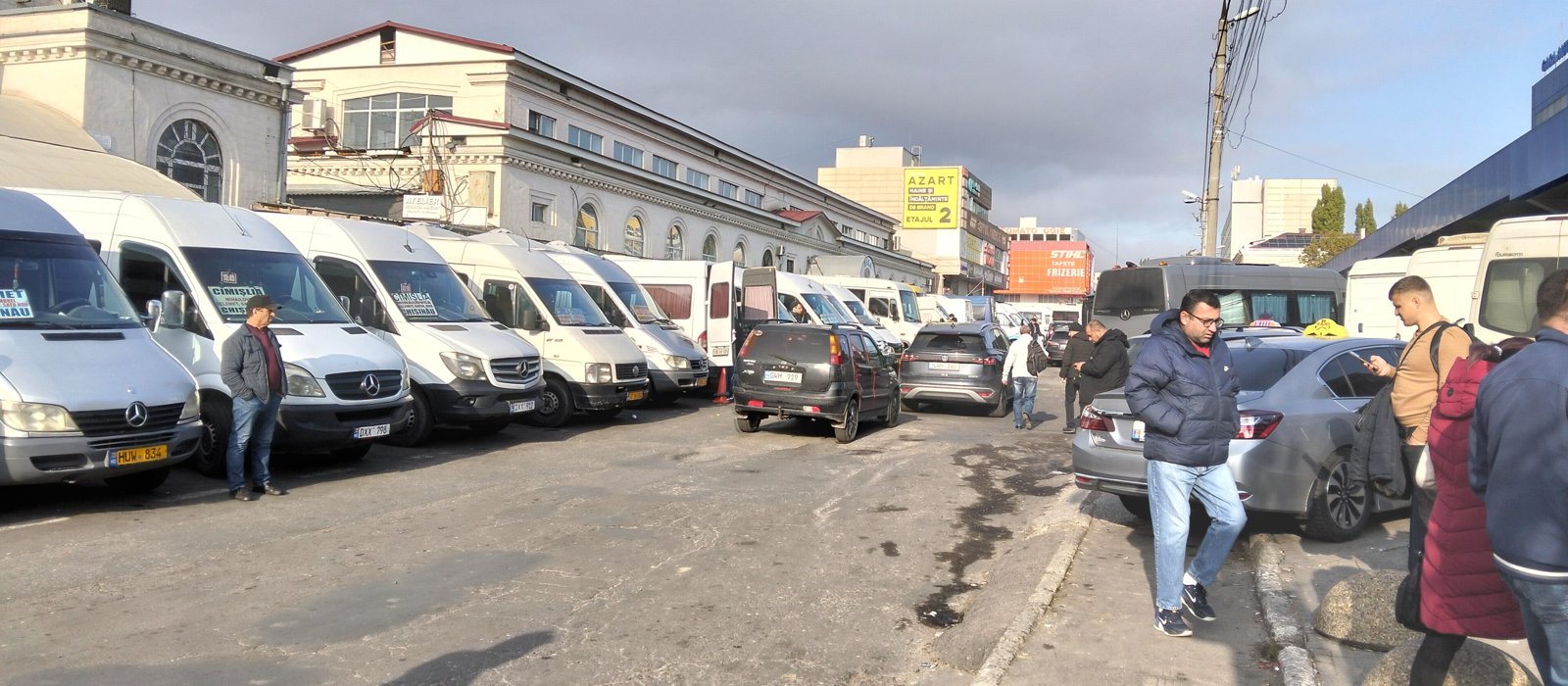 Microbuze albe parcate în rând la autogara centrală din Chișinău, cu pasageri pe trotuar