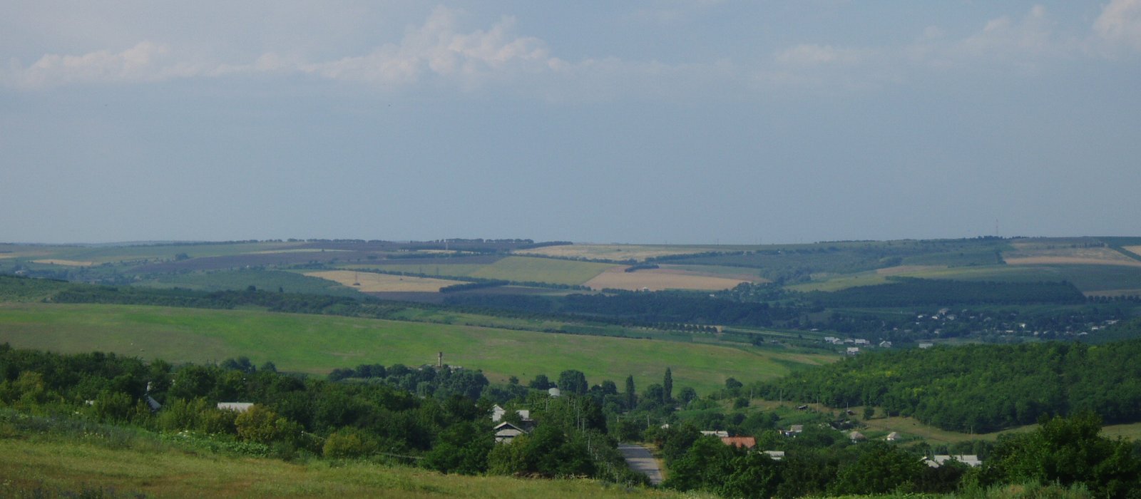 Câmp agricol din Republica Moldova sub un cer larg, cu dealuri la orizont