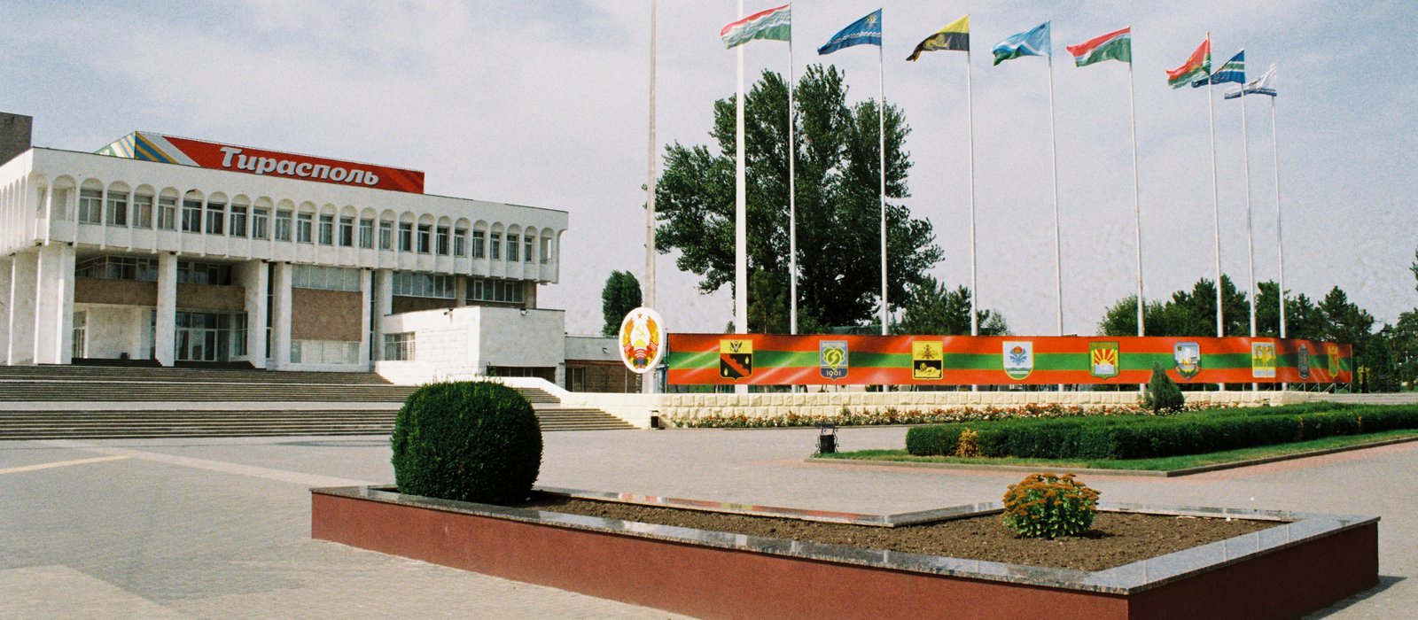 Clădirea cu inscripția Tiraspol și catargele cu steaguri din piața centrală a orașului