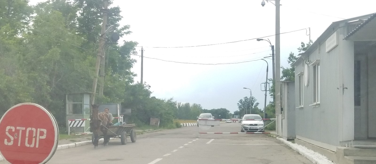 Punct de control vamal cu bară ridicată, o căruță cu cal și o mașină în așteptare la Sănătăuca, Moldova