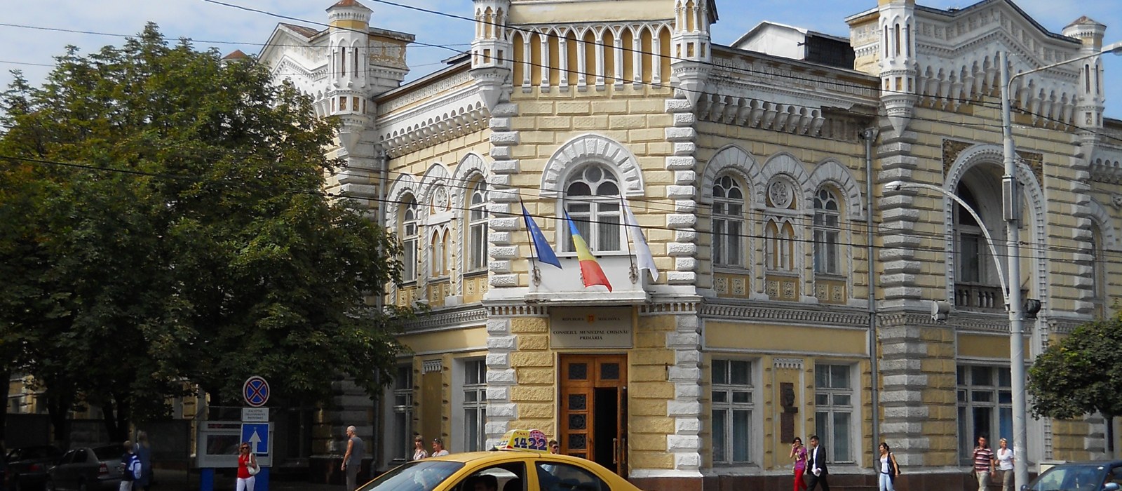 Un taxi galben în fața clădirii Primăriei Chișinău, cu steagurile Uniunii Europene și Republicii Moldova la intrare